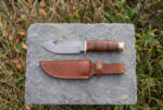 Old Guard D2 gut hook hunting knife with stacked leather handle, brass guard and brown leather sheath on slate