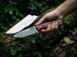 Hazel Drift D2 drop point ladies knife with walnut handle and white leather sheath held in hand on mossy ground