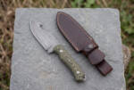 Sagebrush stonewashed D2 gut hook hunting knife with sage green Micarta handle and dark brown leather sheath on slate