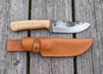 Ashen Oak hand forged high carbon gut hook hunting knife with oak handle and tan leather sheath on weathered decking