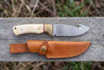 Chalk Meadow satin D2 gut hook hunting knife with cream camel bone handle, brass bolster and tan leather sheath on weathered wood