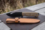 Nightfall black oxide D2 gut hook hunting knife with olive drab Micarta handle and tan leather sheath on a leather mat