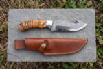 Honey Vein Damascus gut hook hunting knife with amber maple burl handle and brown leather sheath on slate