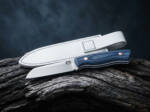 Indigo Shore D2 sheepsfoot ladies knife with navy blue Micarta handle and white leather sheath on driftwood
