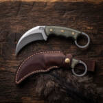 Verdant Reaper satin D2 karambit knife with olive green Micarta handle and oxblood leather sheath on dark wood