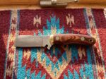 Cinnabar Rain raindrop Damascus cowboy bull cutter knife with rosewood handle and brass bolster on a southwestern wool blanket