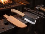 Anvil Song hammer forged carbon steel cowboy bull cutter knife with oak handle and leather sheath on a blacksmith anvil
