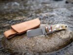 River Pearl satin D2 cowboy bull cutter knife with mother of pearl handle, brass bolster and leather sheath on wet river stones