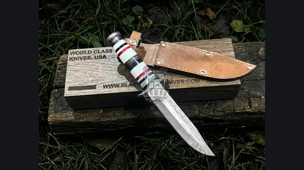 Full-tang Damascus drop point hunting knife with stag handle on autumn leaves