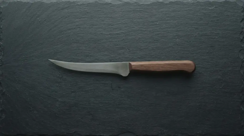 A slim flexible boning knife alone on dark slate