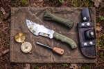 Jade Warden mirror polished D2 steel Tom Brown style tracker knife with olive green G10 handle, shown with bushcraft kit