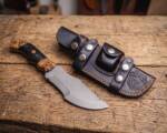Ember Burl D2 steel Tom Brown style tracker knife with black micarta handle, olive burl wood bolsters, brass pipe inlay and black leather tracker sheath