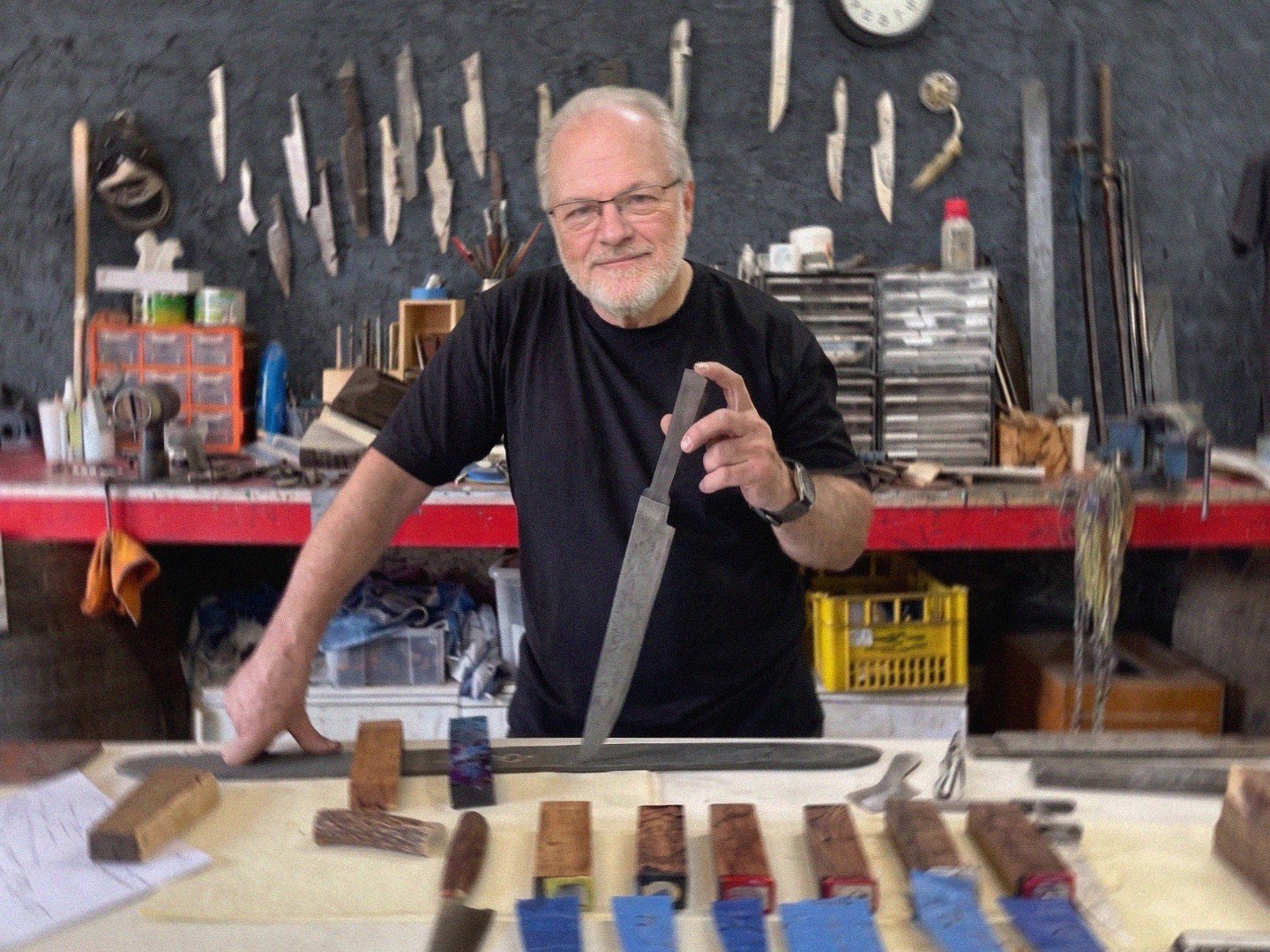 Mark Kovalsky holding a finished blade at his workbench in the Black Mamba workshop